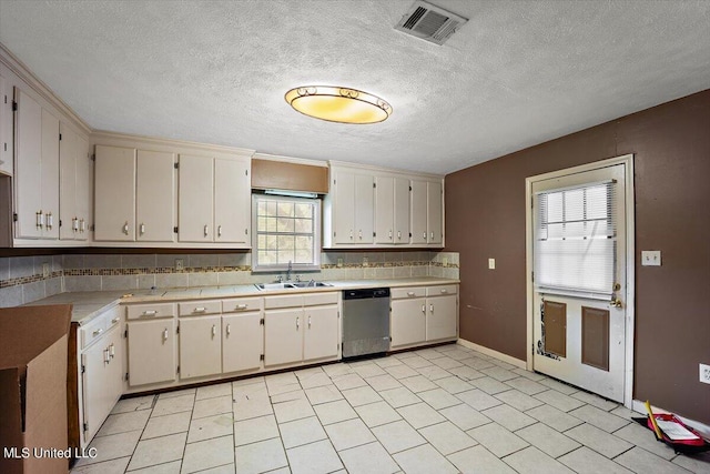 kitchen featuring stainless steel dishwasher, a textured ceiling, a sink, light countertops, and visible vents