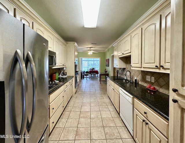 kitchen featuring a sink, a ceiling fan, backsplash, and stainless steel appliances
