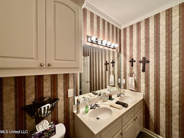 bathroom featuring double vanity, a sink, ornamental molding, and wallpapered walls