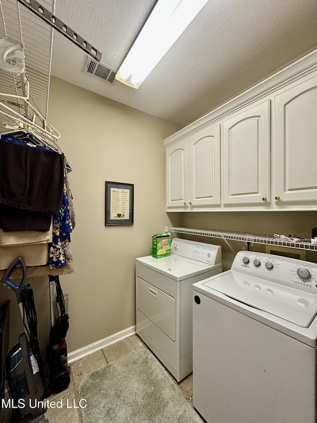 clothes washing area with visible vents, cabinet space, light tile patterned floors, baseboards, and separate washer and dryer