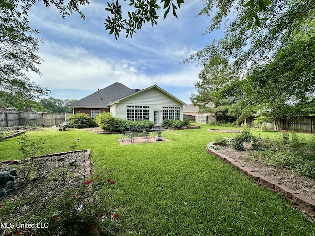 rear view of house featuring a fenced backyard and a yard
