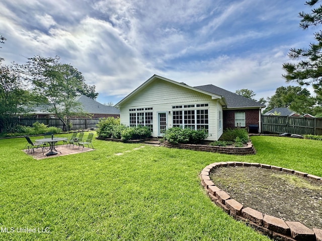 rear view of property featuring a fenced backyard, a patio, a yard, and brick siding