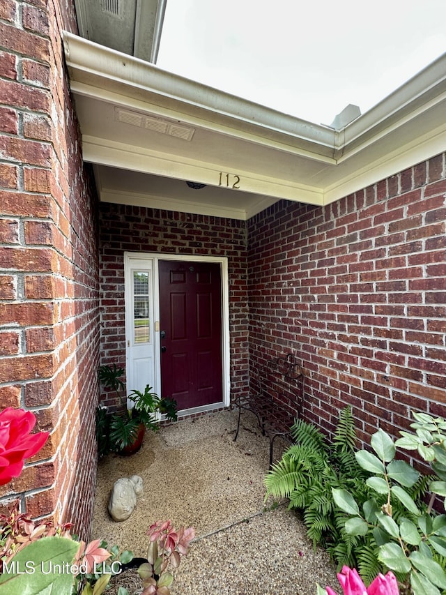 view of exterior entry featuring brick siding