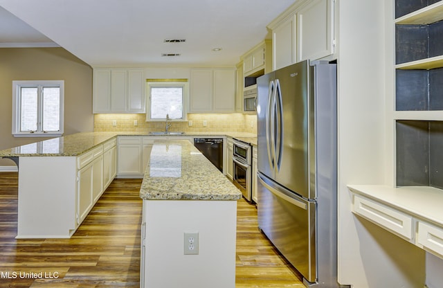 3099 E Fairway Dr, Brandon, MS 39047 - kitchen with appliances with stainless steel finishes, a sink, a kitchen island, light wood-type flooring, and a peninsula