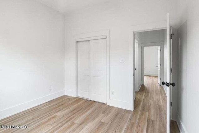 unfurnished bedroom with light hardwood / wood-style flooring and a closet