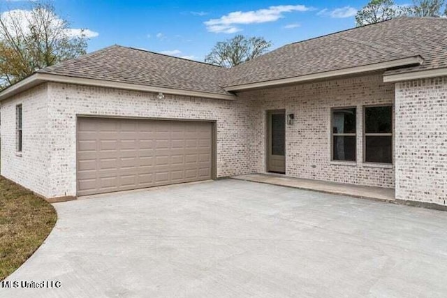 view of front of property featuring a garage, concrete driveway, brick siding, and a shingled roof