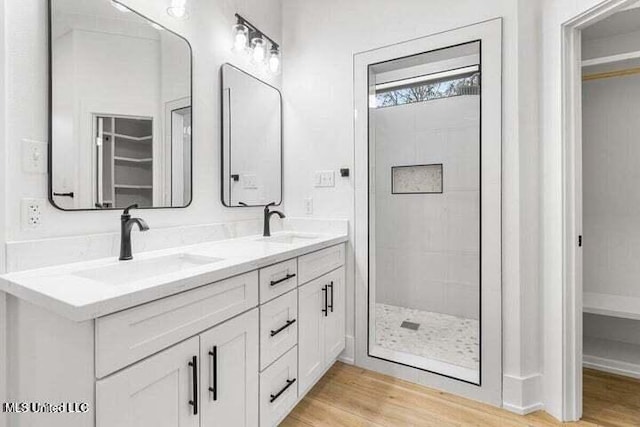 bathroom with hardwood / wood-style floors, vanity, and a tile shower