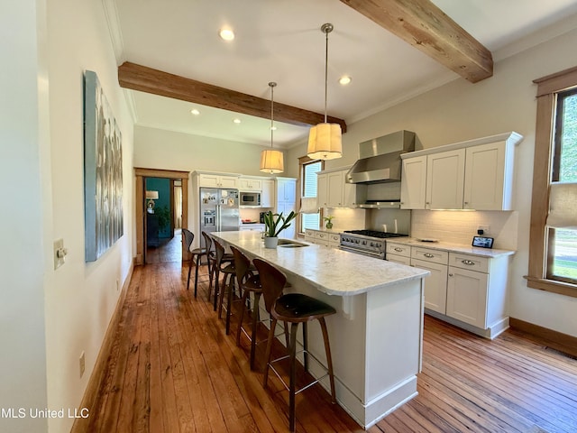 101 E E President, Greenwood, MS 38930 - kitchen with high quality appliances, wall chimney exhaust hood, beam ceiling, plenty of natural light, and tasteful backsplash