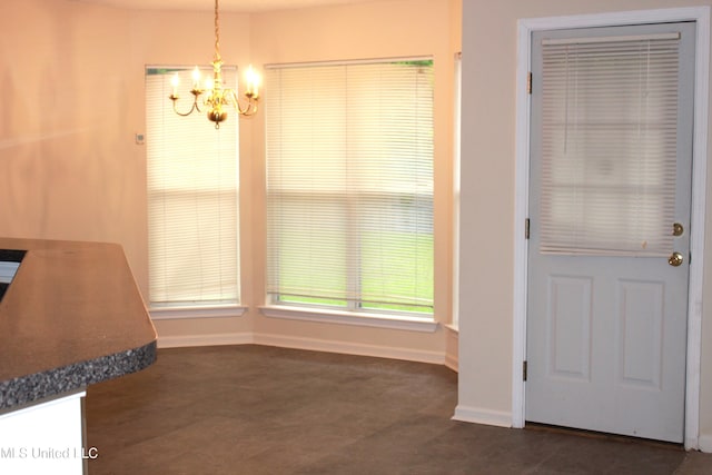 unfurnished dining area with a chandelier and baseboards