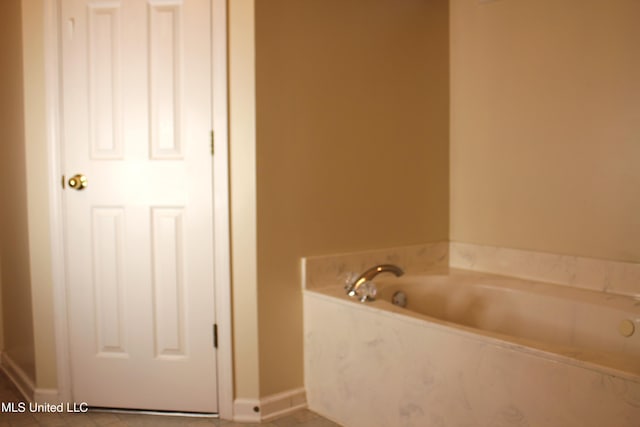 bathroom with a garden tub and baseboards