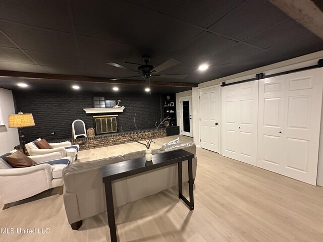 1529 Ticonderoga Dr, Southaven, MS 38671 - living room with light wood-style flooring, ceiling fan, a fireplace, a barn door, and a paneled ceiling