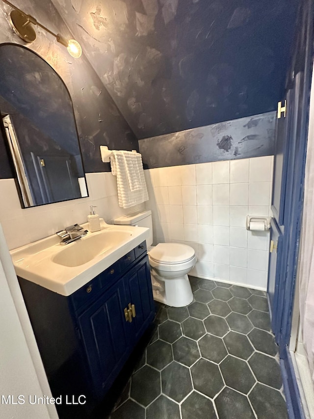1529 Ticonderoga Dr, Southaven, MS 38671 - bathroom with tile walls, vanity, vaulted ceiling, toilet, and tile patterned floors