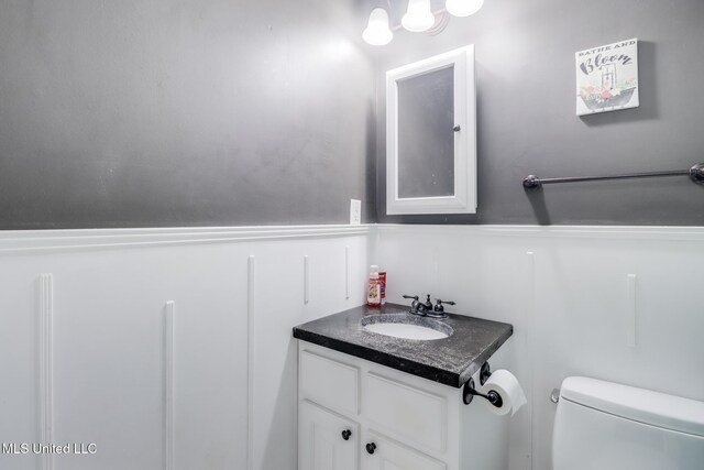 bathroom with a wainscoted wall, toilet, and vanity