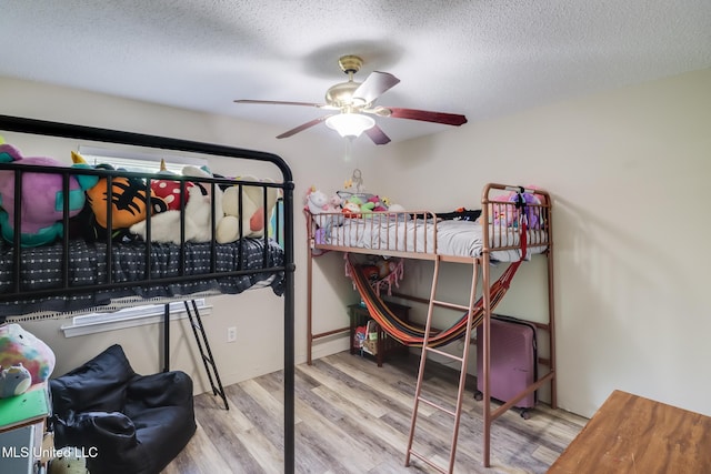 bedroom with a textured ceiling, a ceiling fan, and wood finished floors