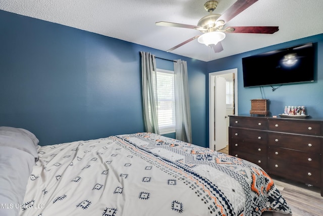 bedroom featuring a textured ceiling, wood finished floors, and ceiling fan