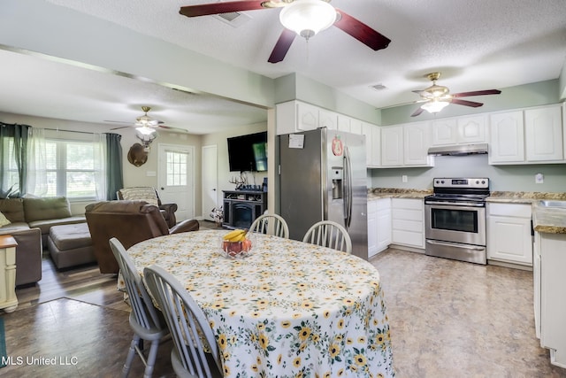 kitchen featuring ceiling fan, appliances with stainless steel finishes, open floor plan, and a textured ceiling
