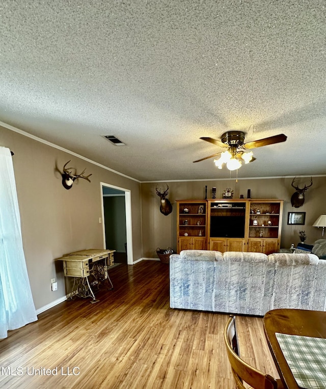 living room with hardwood / wood-style floors, a textured ceiling, ceiling fan, and ornamental molding