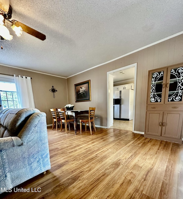 dining space with ceiling fan, light hardwood / wood-style flooring, a textured ceiling, and ornamental molding