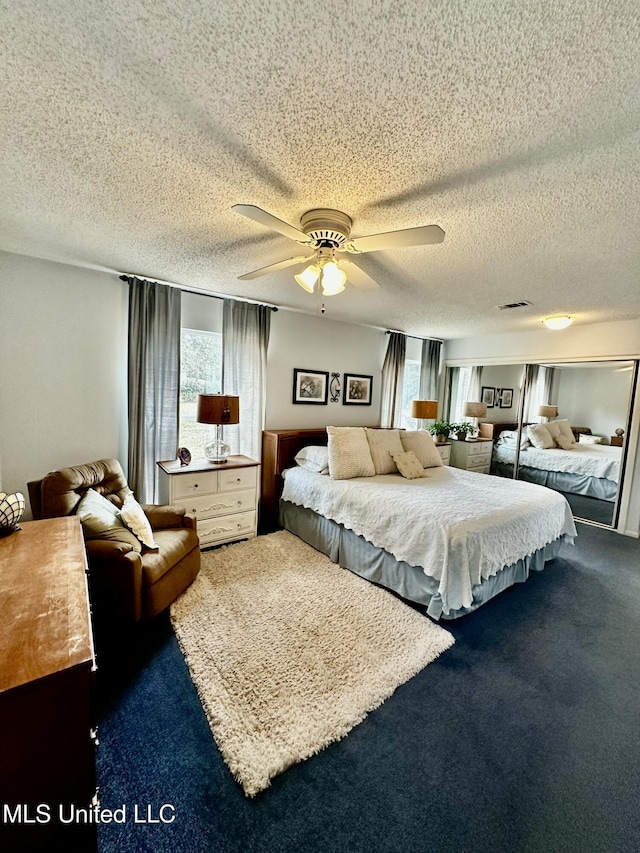 carpeted bedroom with multiple windows, ceiling fan, and a textured ceiling