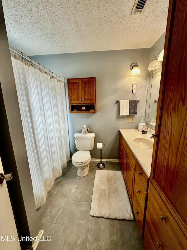 bathroom featuring vanity, a textured ceiling, and toilet