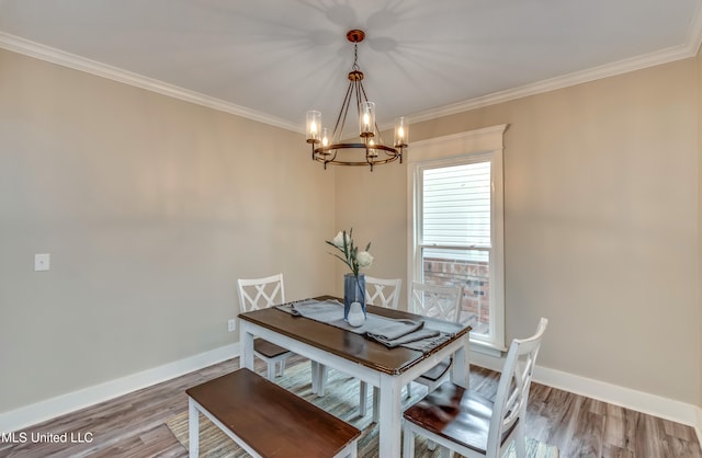 dining space with wood-type flooring, crown molding, and an inviting chandelier