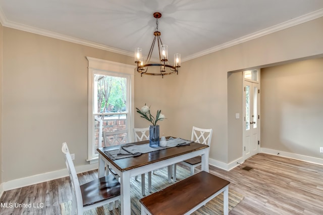 dining space with light hardwood / wood-style floors, a notable chandelier, and crown molding