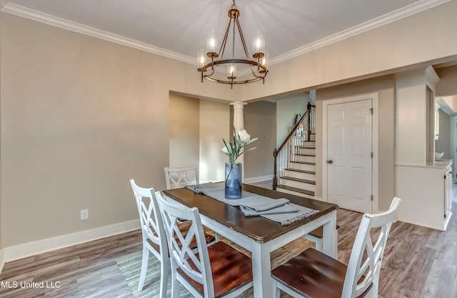 dining space featuring decorative columns, a chandelier, hardwood / wood-style floors, and crown molding