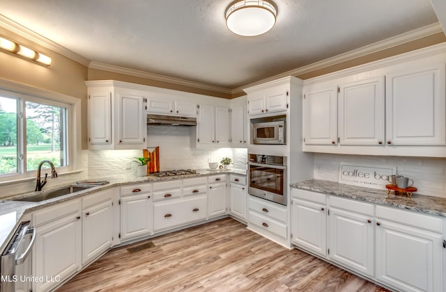 kitchen featuring light hardwood / wood-style floors, white cabinetry, sink, appliances with stainless steel finishes, and tasteful backsplash