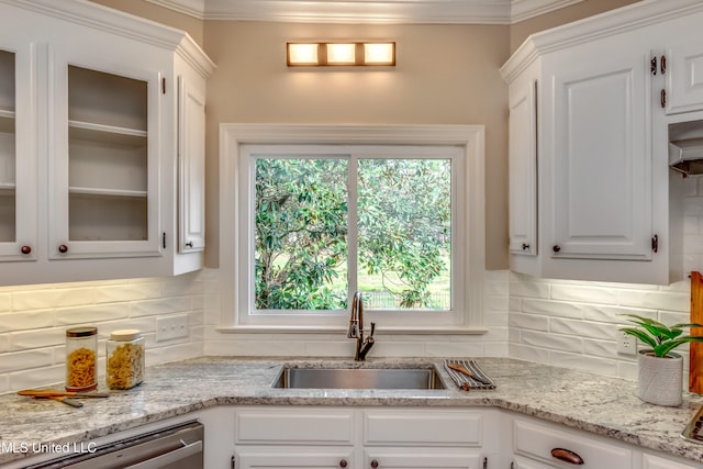 kitchen with light stone counters, sink, stainless steel dishwasher, backsplash, and white cabinetry