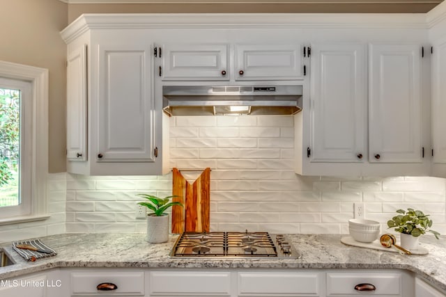 kitchen with range hood, white cabinetry, stainless steel gas cooktop, and tasteful backsplash