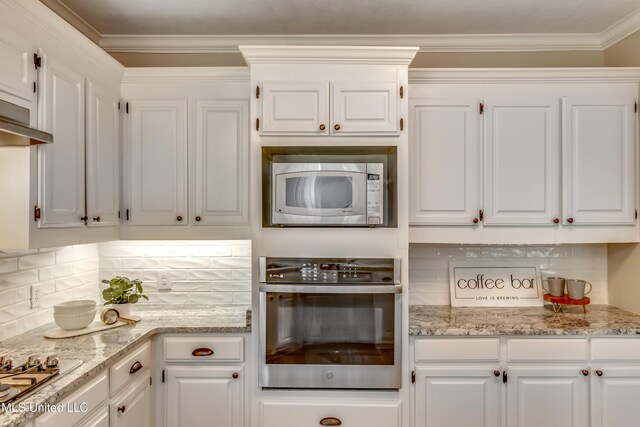 kitchen featuring tasteful backsplash, ornamental molding, stainless steel appliances, white cabinetry, and light stone countertops