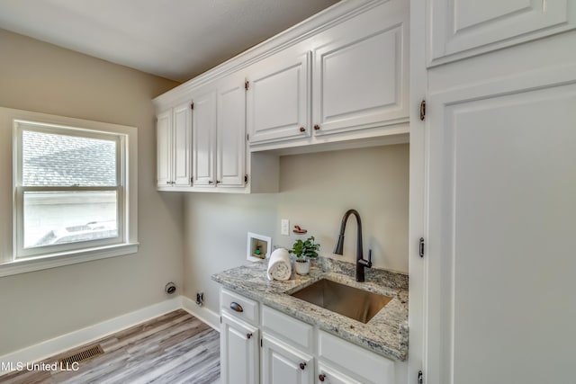 clothes washing area featuring cabinets, light hardwood / wood-style floors, sink, hookup for a washing machine, and hookup for a gas dryer