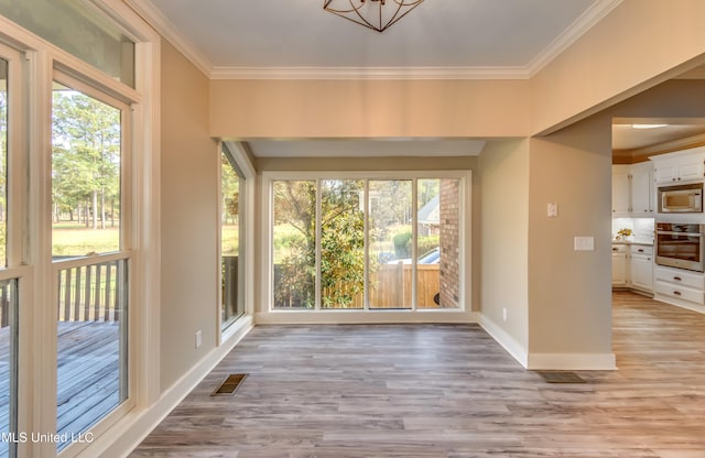 interior space with ornamental molding, light hardwood / wood-style floors, and a healthy amount of sunlight