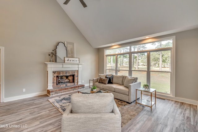 living room featuring hardwood / wood-style floors, ceiling fan, a fireplace, and high vaulted ceiling