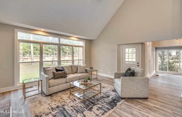 living room with high vaulted ceiling, a wealth of natural light, and light wood-type flooring