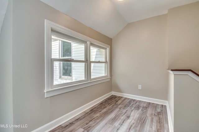 unfurnished room with light wood-type flooring and lofted ceiling