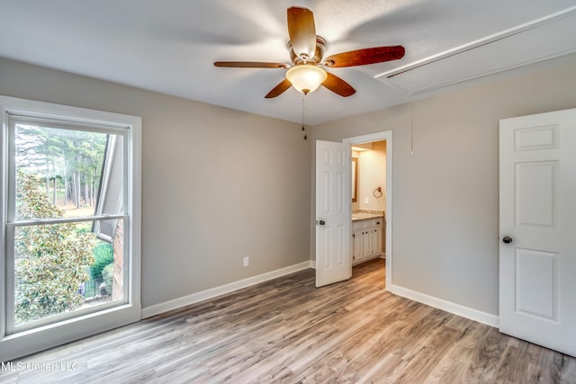 unfurnished bedroom featuring light wood-type flooring, ceiling fan, and connected bathroom