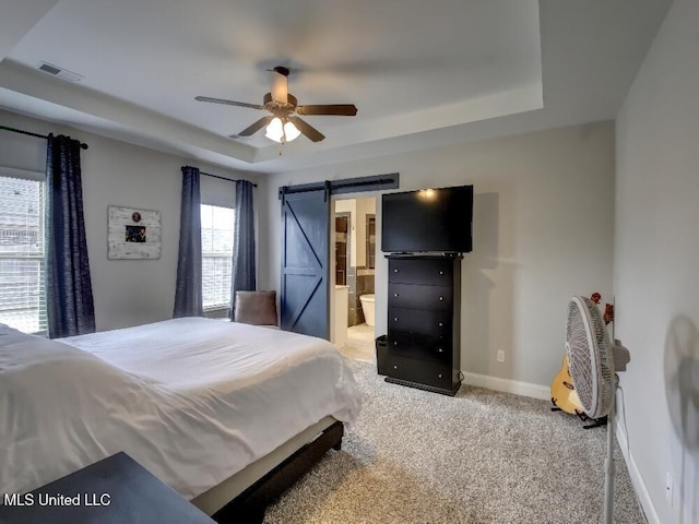 bedroom with a barn door, light colored carpet, multiple windows, and ceiling fan