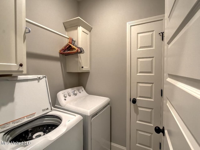 laundry room with separate washer and dryer and cabinets