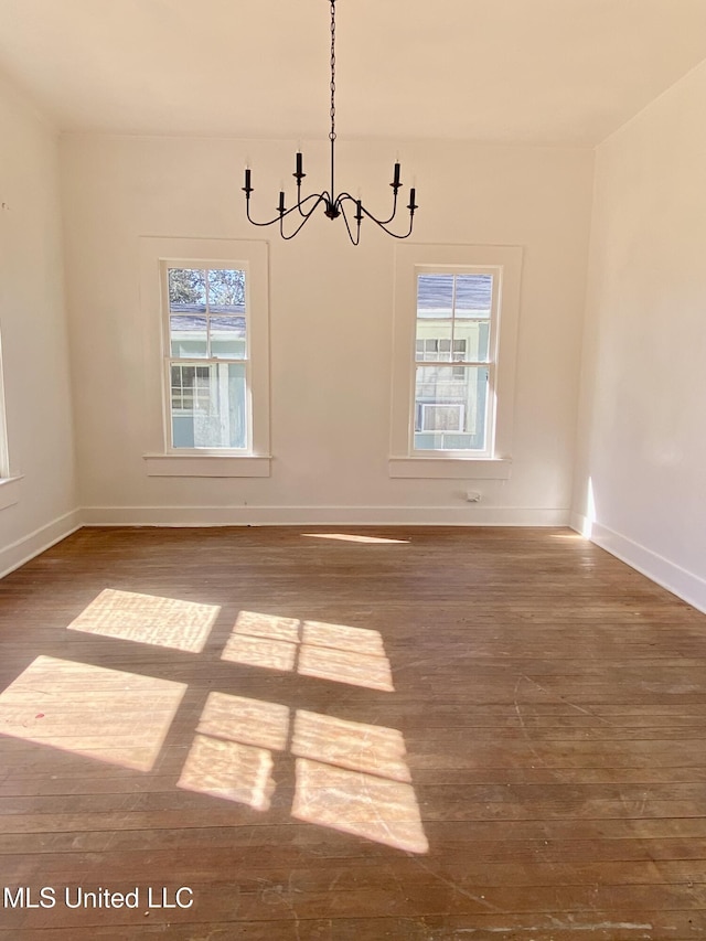 unfurnished dining area featuring baseboards, a chandelier, and wood finished floors