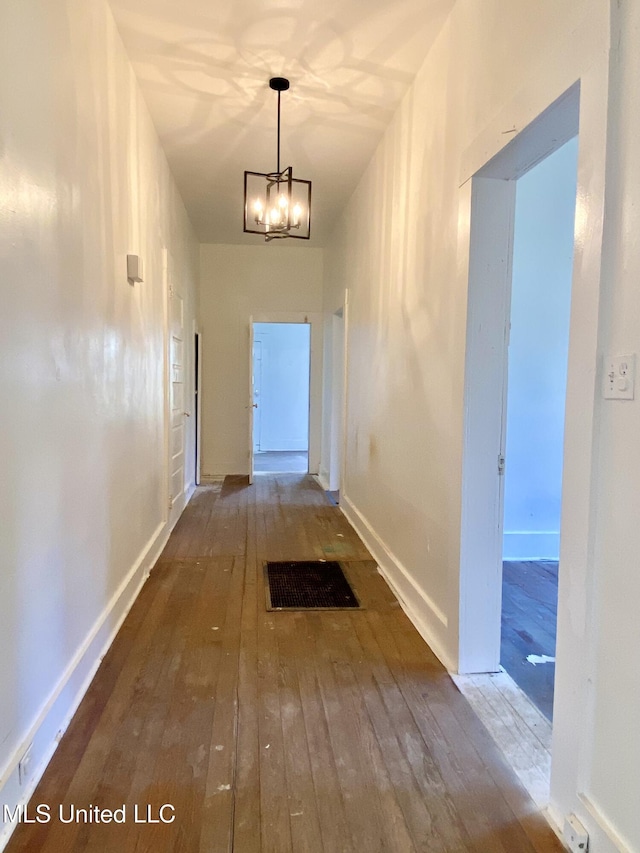 hall with a chandelier, baseboards, visible vents, and hardwood / wood-style floors