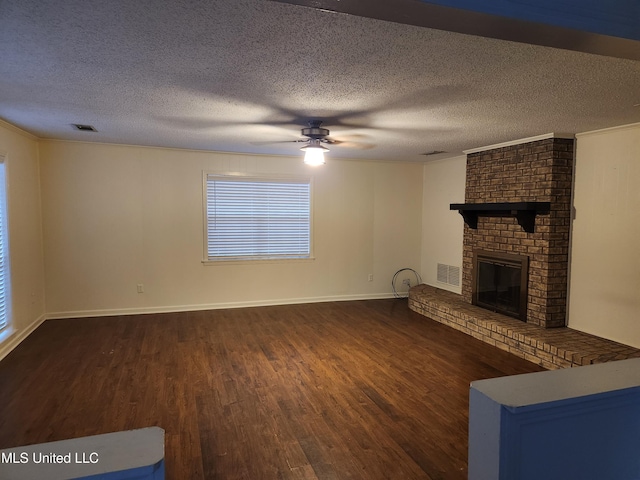 unfurnished living room with ceiling fan, dark hardwood / wood-style flooring, a textured ceiling, and a brick fireplace