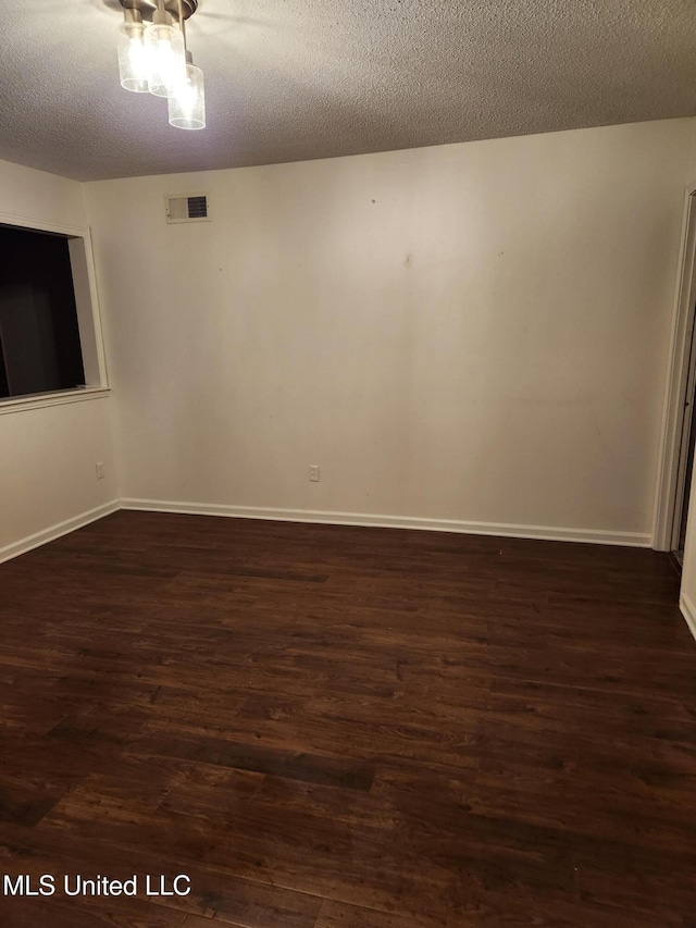 unfurnished room with a textured ceiling and dark hardwood / wood-style floors