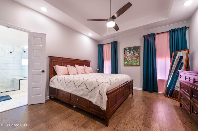 bedroom with ceiling fan, a tray ceiling, and dark hardwood / wood-style flooring