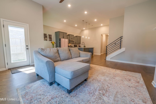 living room with sink, vaulted ceiling, and dark wood-type flooring