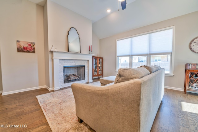 living room featuring vaulted ceiling, a fireplace, ceiling fan, and dark hardwood / wood-style floors