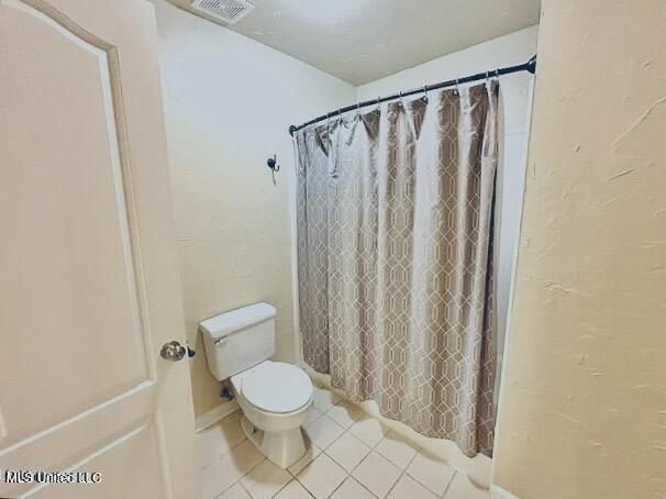 bathroom featuring curtained shower, tile patterned floors, and toilet