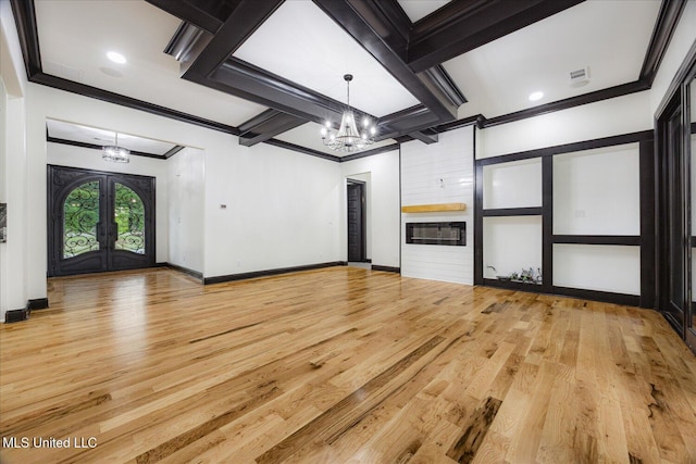 unfurnished living room featuring crown molding, a chandelier, french doors, and light wood-type flooring