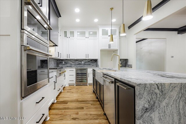 kitchen featuring wine cooler, light wood-style floors, white cabinetry, tasteful backsplash, and stainless steel appliances