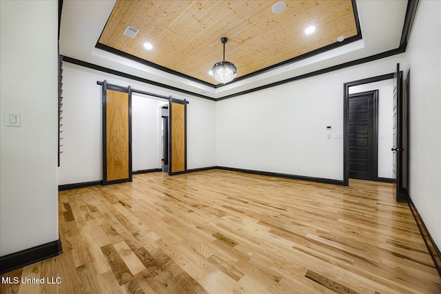 unfurnished room featuring baseboards, a tray ceiling, light wood finished floors, and visible vents